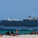 A cruise ship sails in the background as people relax in Miami Beach, Florida on July 2, 2020.